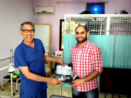 Dr Francis delivers a portable neuro-muscular electrical stimulator to the Medical Centre in Tripoli.