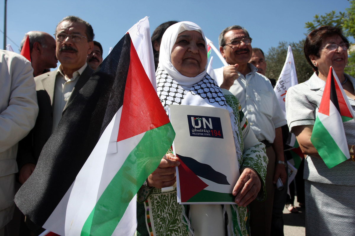 Palestinians hold banners and flags as they march during the launch of a campaign supporting a bid for Palestinian statehood recognition at the U.N, in the West Bank city of Ramallah on Sep. 8, 2011. A member of the campaign handed a letter intended…