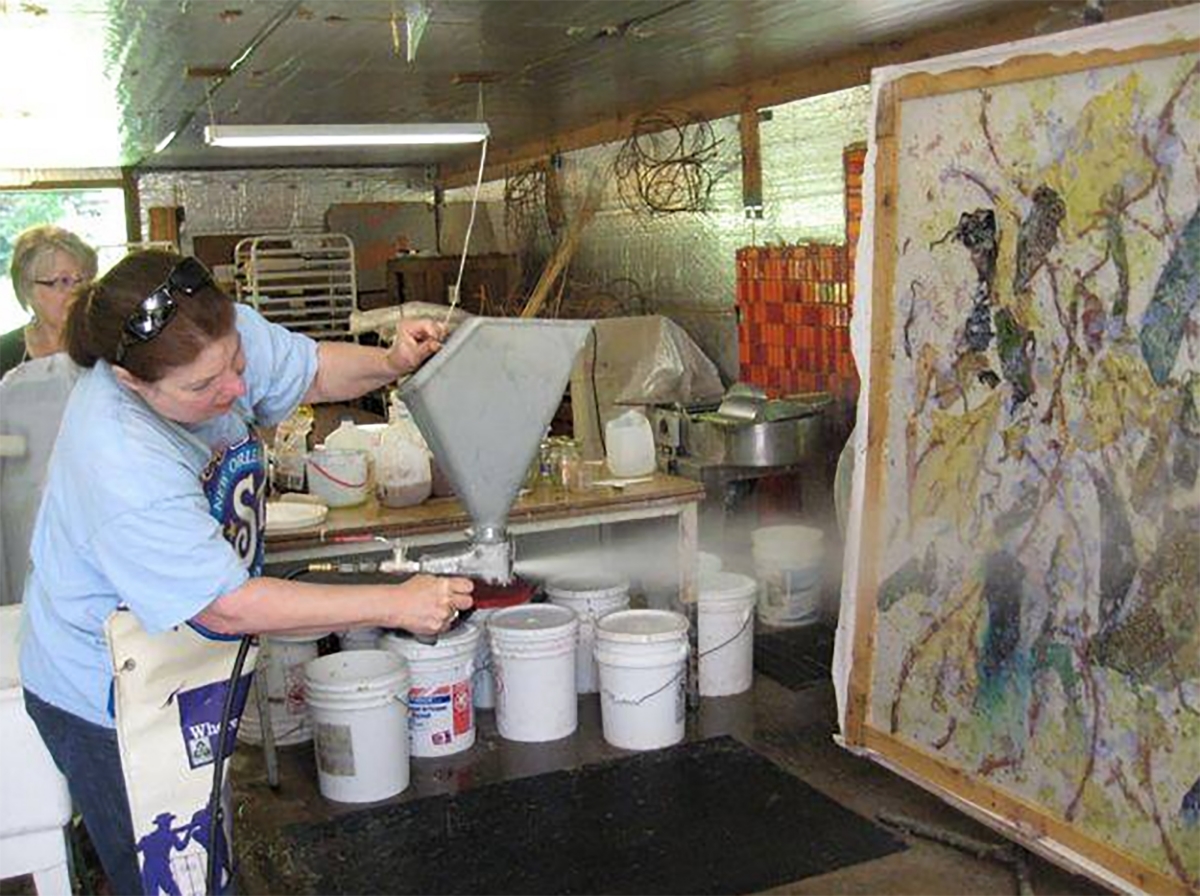  Kathleen is spraying another layer of pulp on her paper piece with fabric and plant inclusions between the layers. 