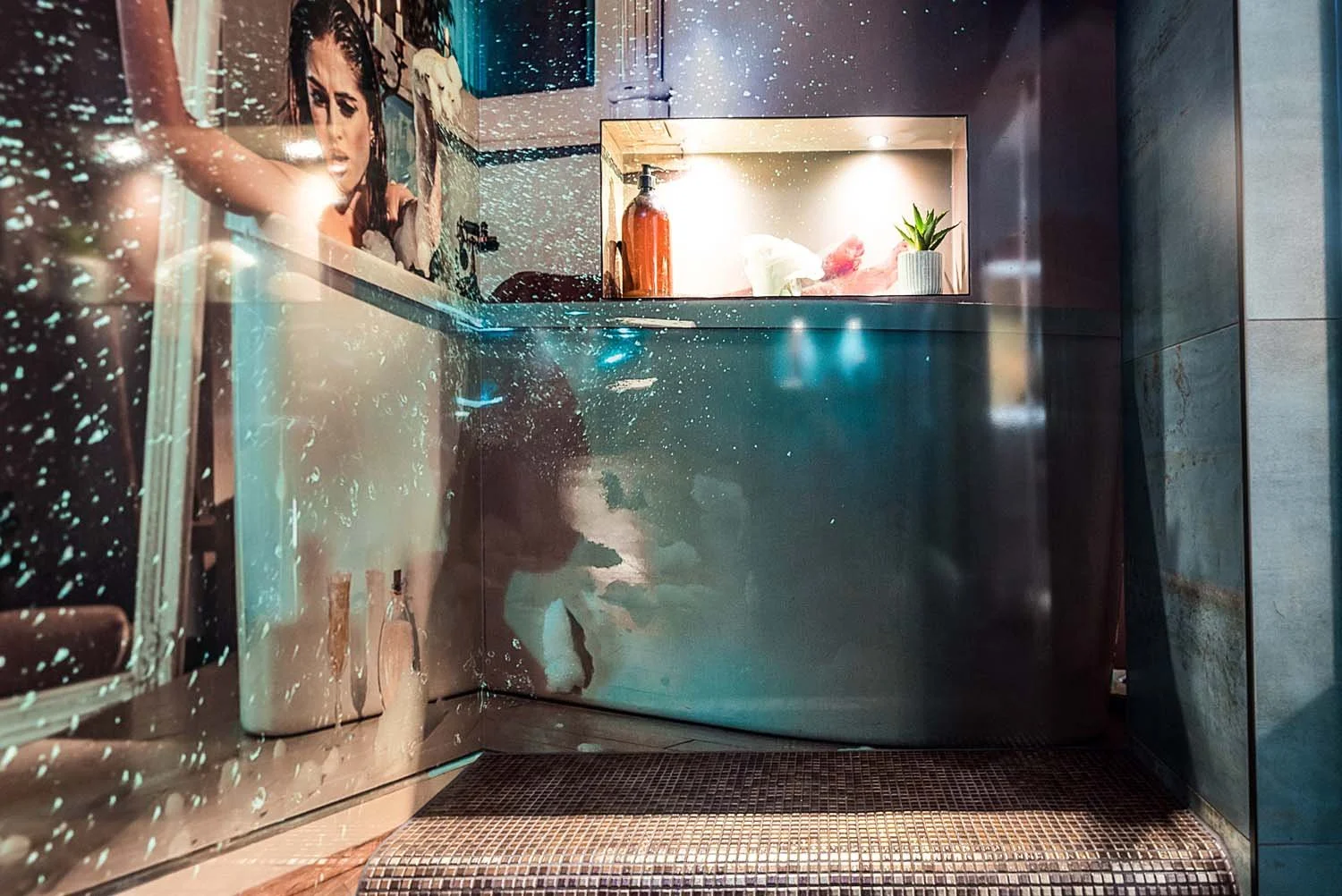 Image of brunette female splashing in the bath, photograph printed to a shower wall within a residential steam room space.