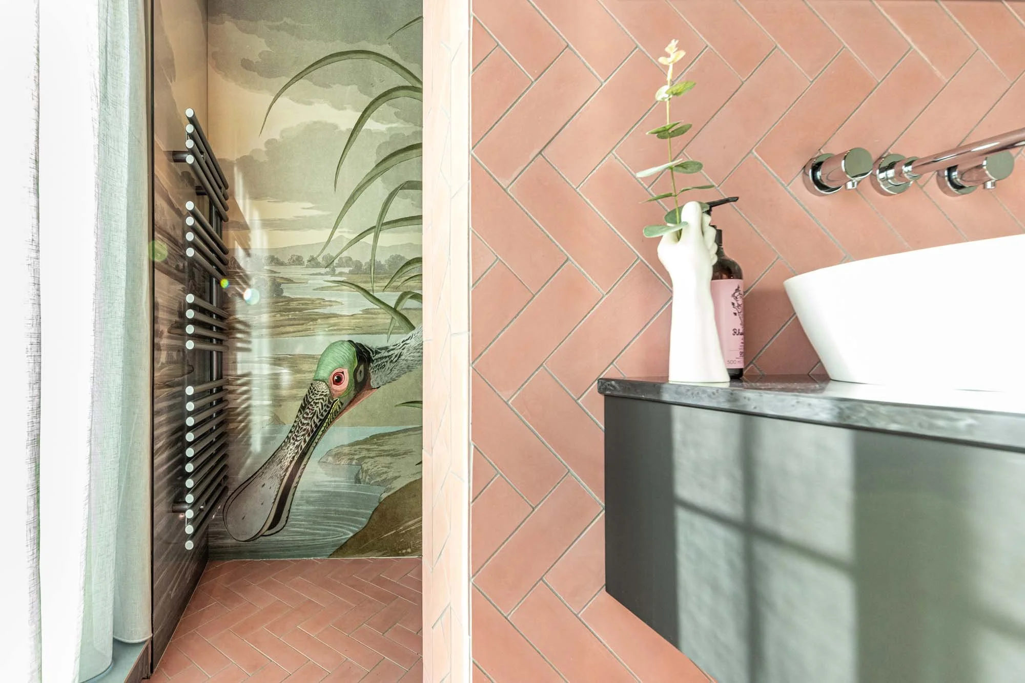Modern bathroom interior design with art print wall panels, matching pink and green bathroom furniture and wall and floor tiling.