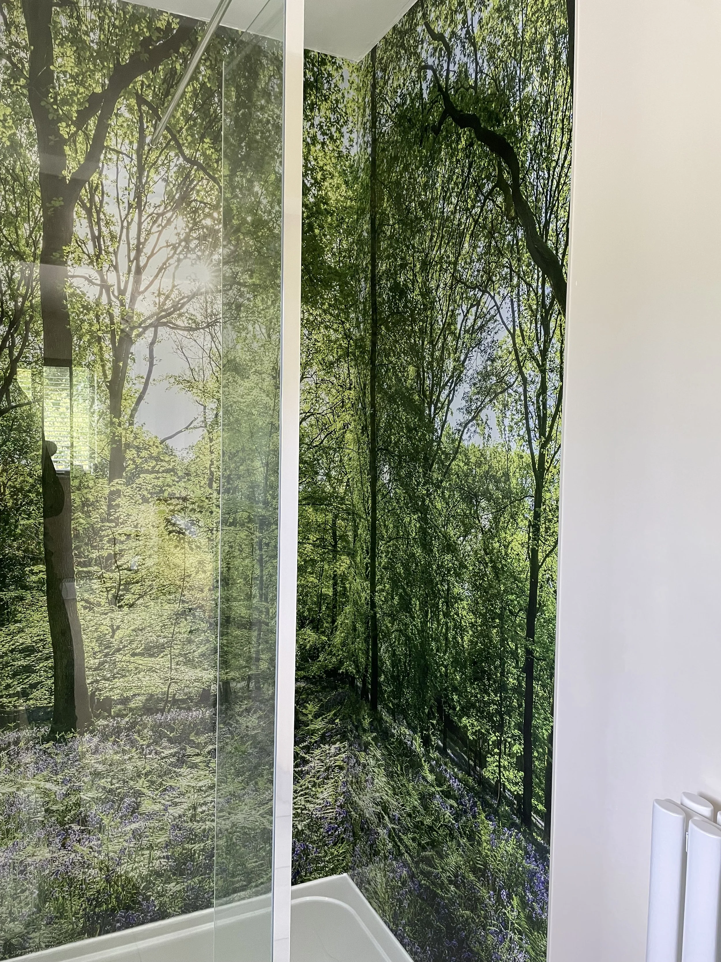 Woodland image shower wall panels wrapping seamlessly around a shower corner, with minimal frameless glass shower screen.