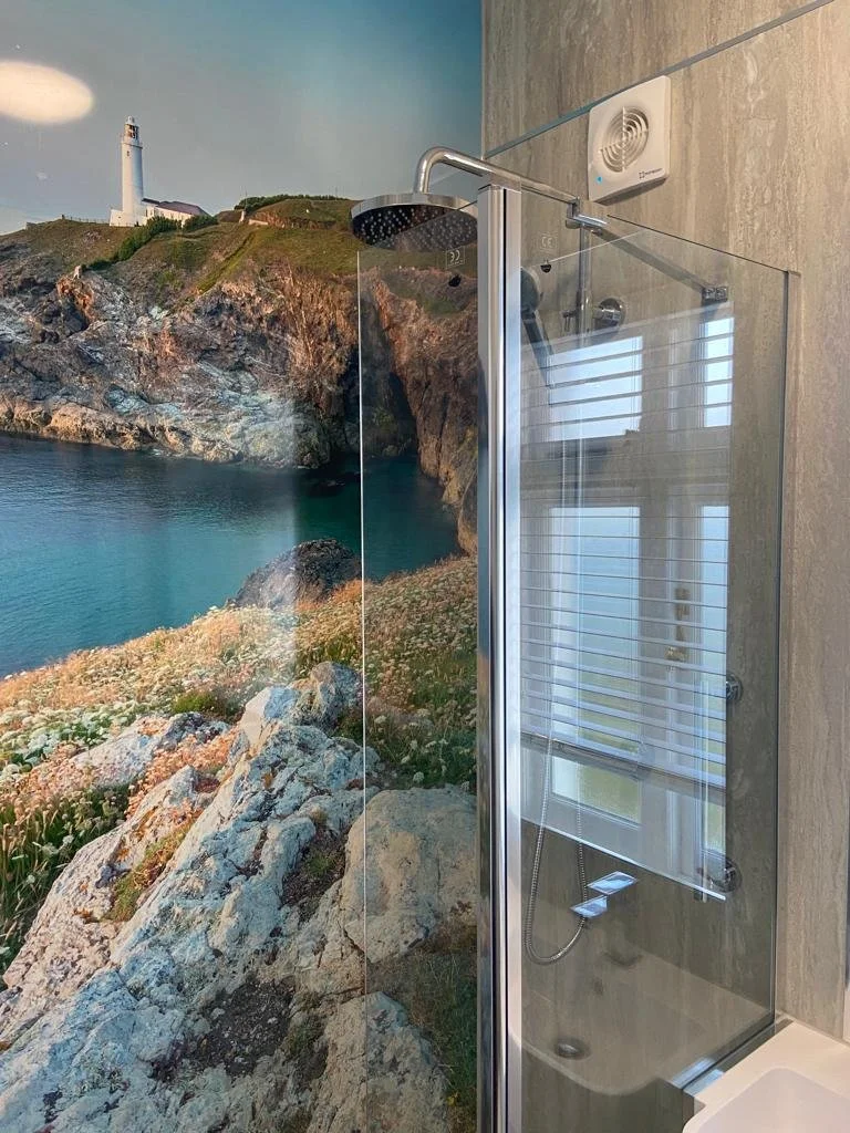 Shower room with glass shower screen, large image panel along far wall with lighthouse photograph