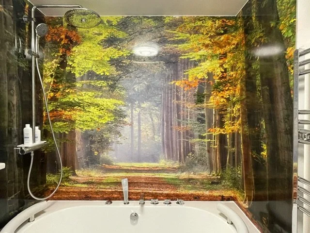 Autumnal woodland image as a feature wall above a bath. Rich, warm yellow, gold and brown tones.