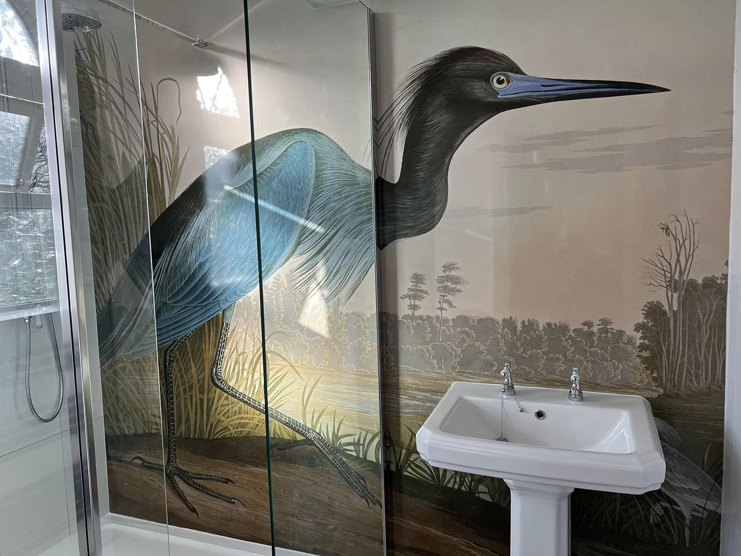 Blue Crane print shower panels installed in a customer bathroom. Bird print bathroom feature wall with white basin and glass shower enclosure