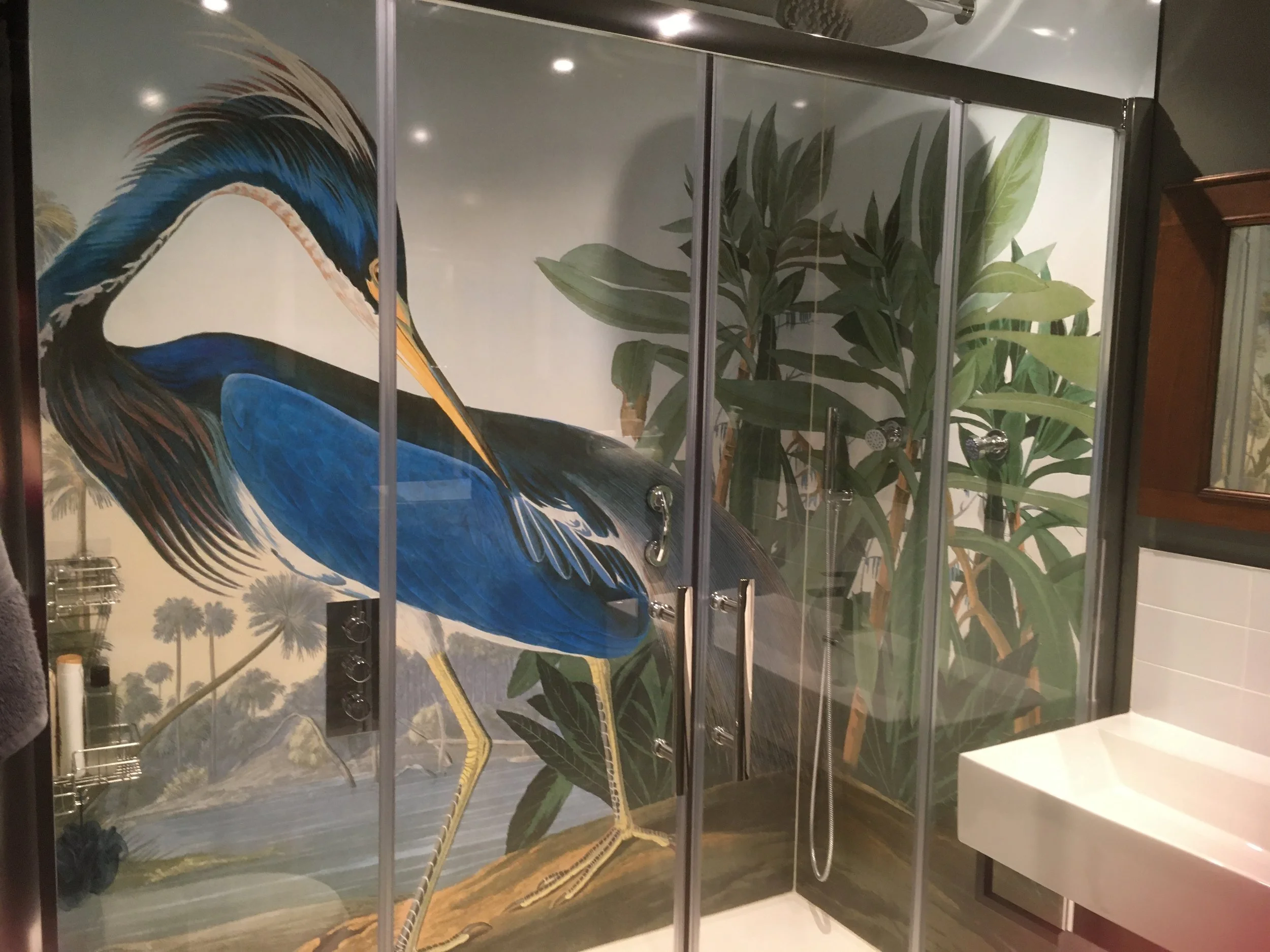 Louisiana Heron print shower panel installed in a modern bathroom. Heron print wraps around the shower walls, with sliding glass doors shower enclosure.