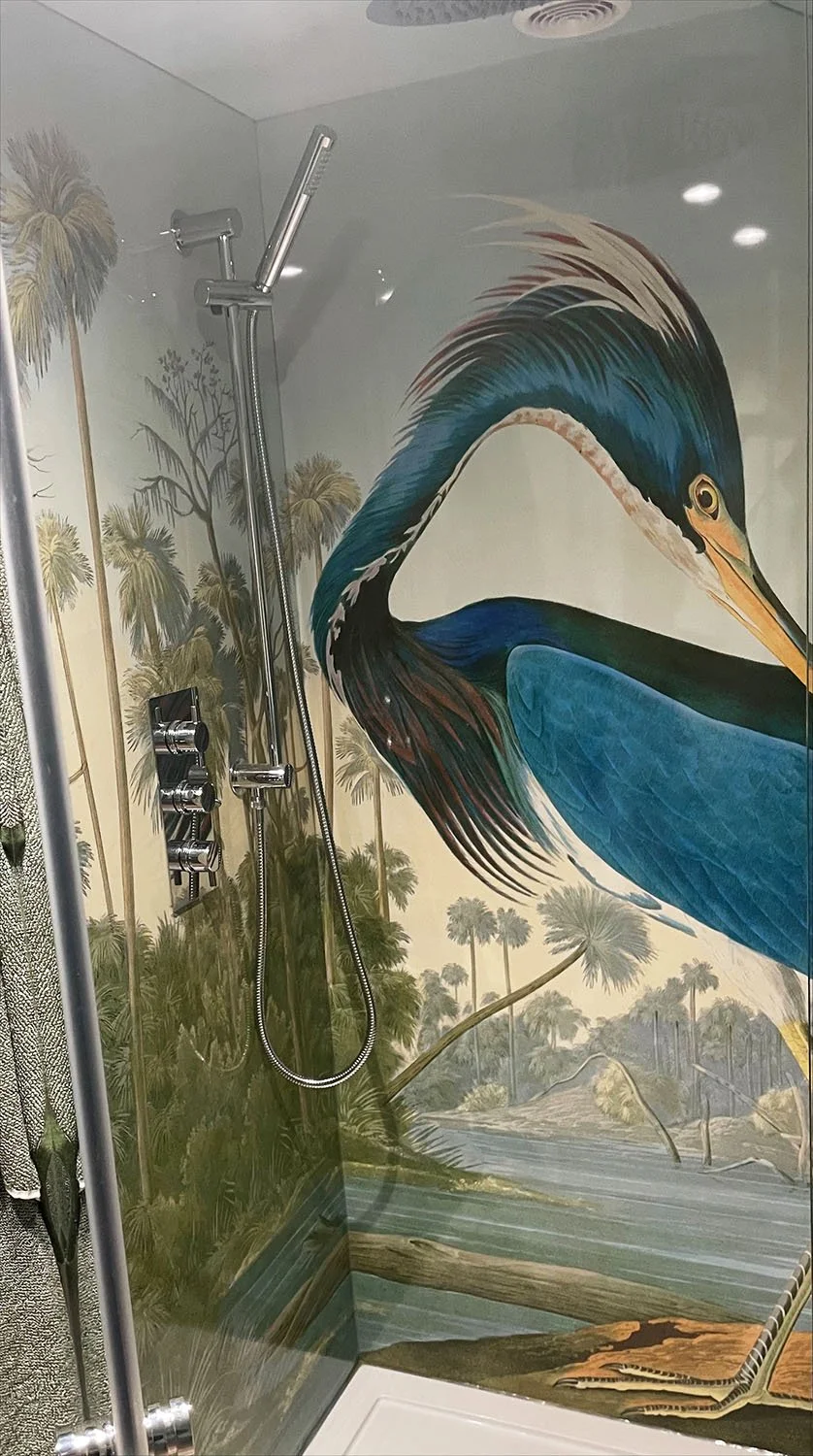 Louisiana Heron Shower panels applied to a shower enclosure in a customer's home. Heron print head and beak behind Chrome shower mixer and riser and clear glass enclosure.