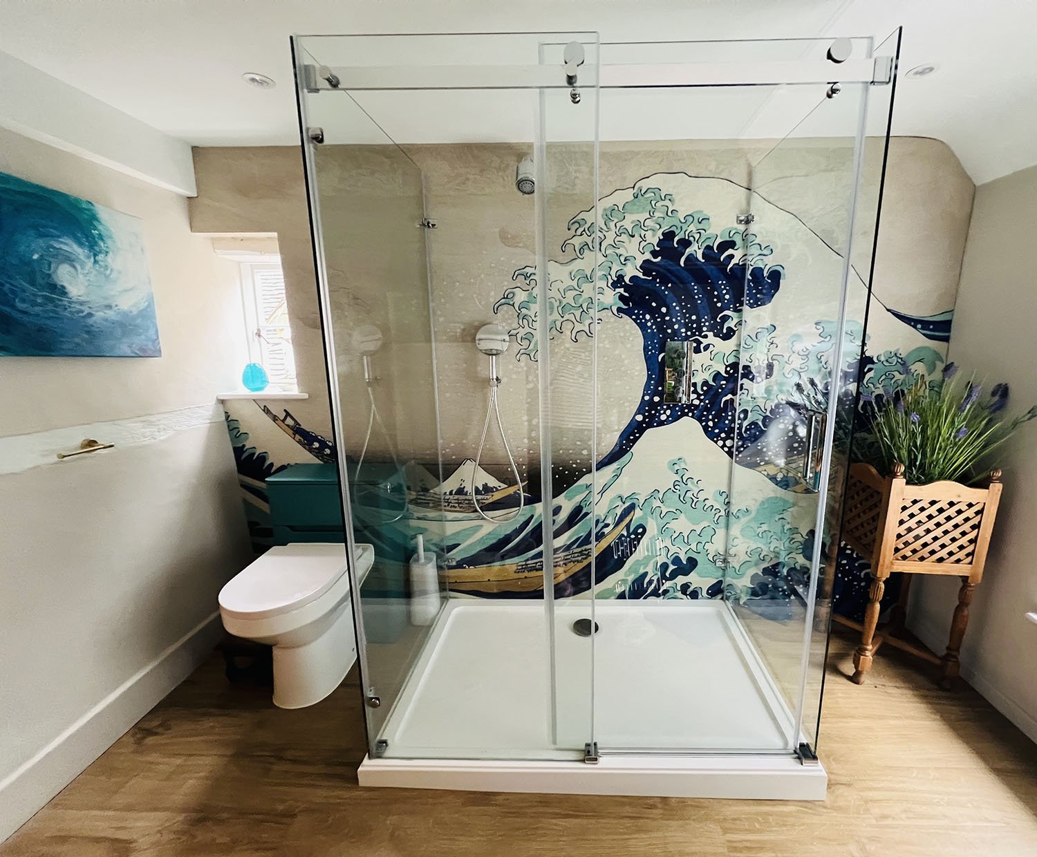 The Great Wave, japanese art print bathroom feature wall. Bathroom install with clear glass shower enclosed in the centre of a wall, wooden floor, traditional UK home.