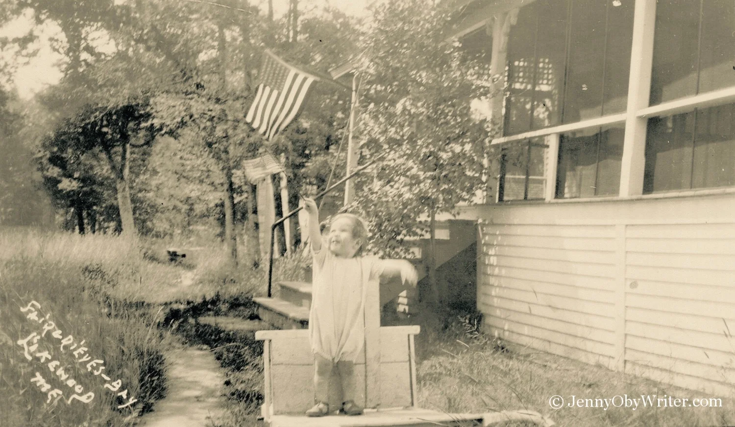 A child waves the American flag outside one of the small cottages that were part of the "resort" at Fairgrieve's Bay on Lake Wesserunsett.