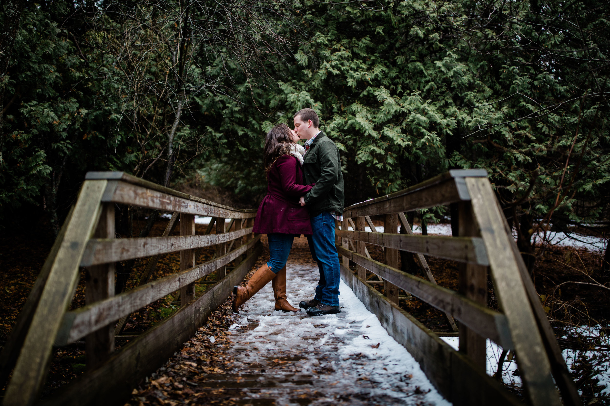 Libby and Alex kiss on a snowy bridge.
