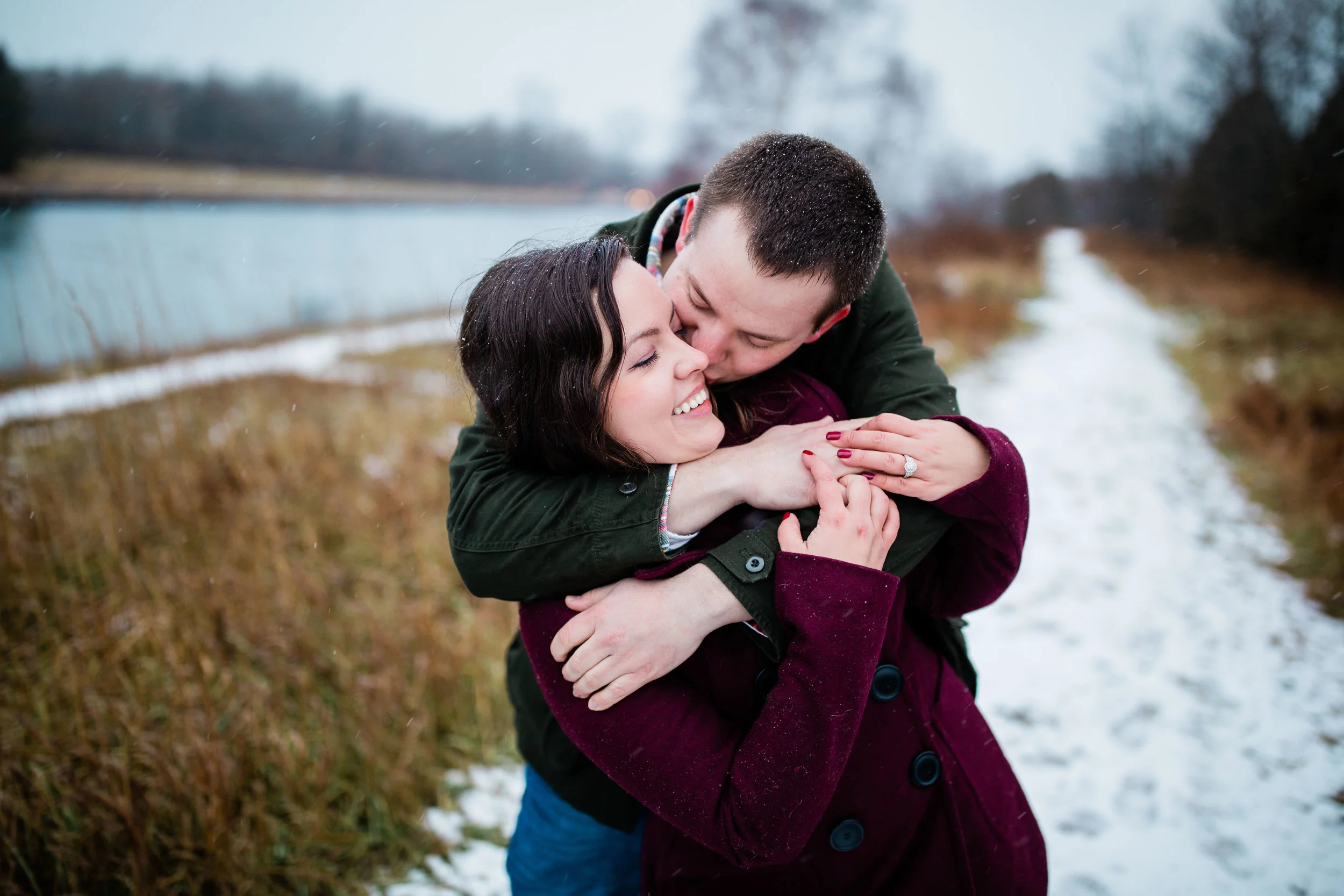 Alex gives Libby a big hug and kiss from behind on a snowy trail.