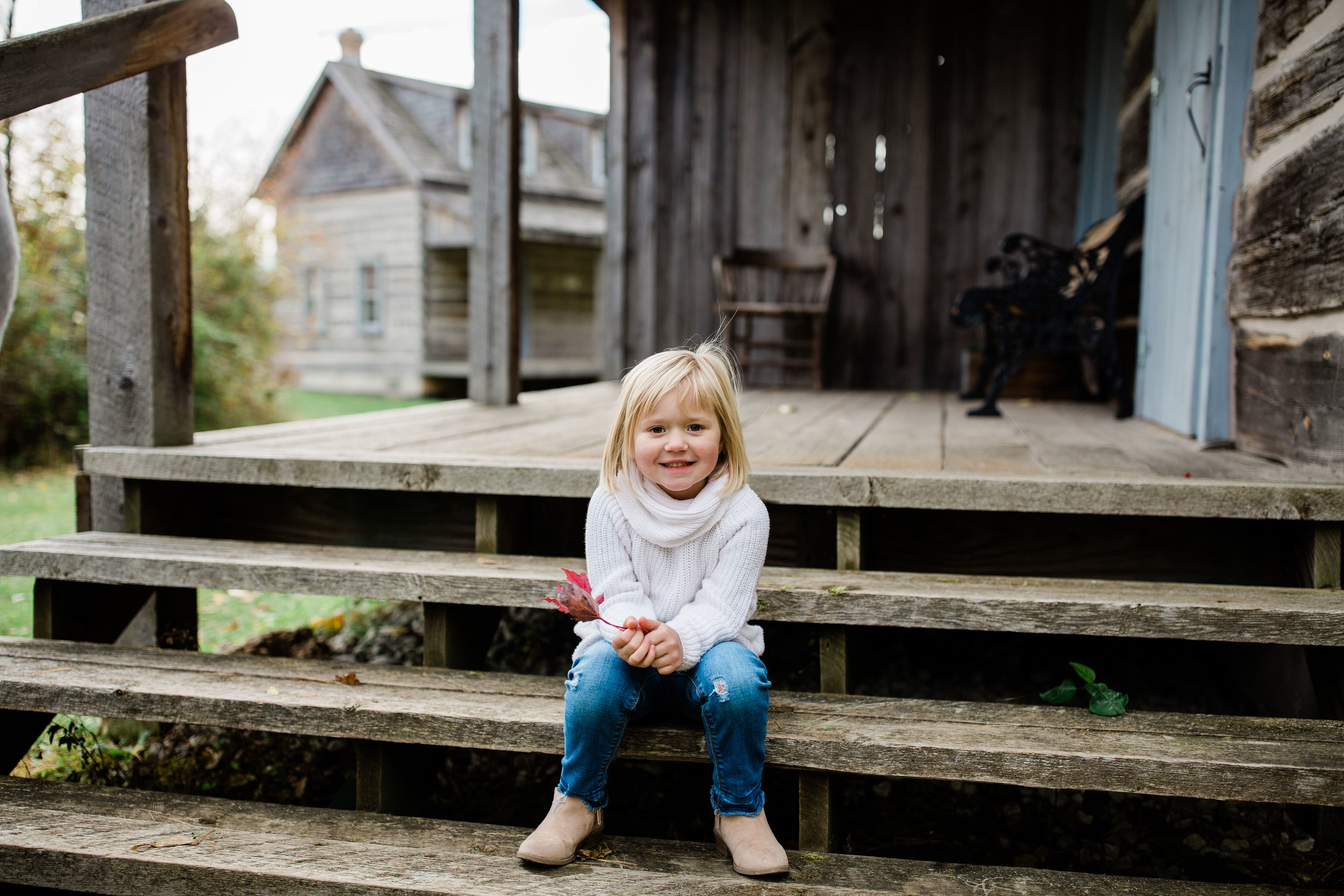 Myra sitting on rustic steps with a leaf.