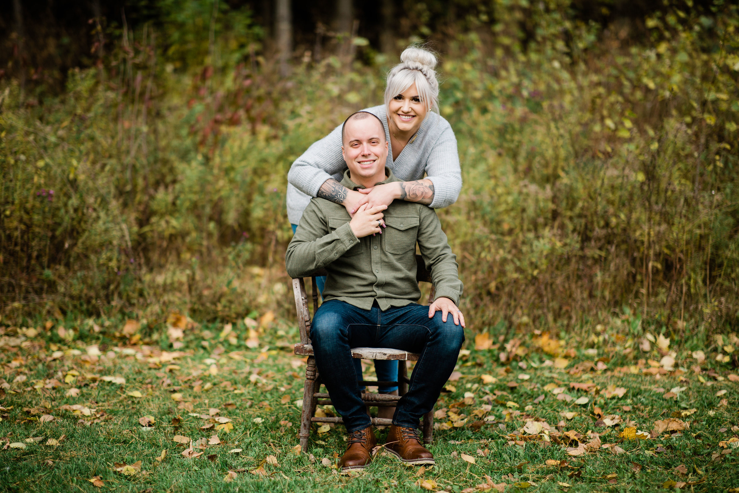 Ali and Jacob in a meadow sitting on a vintage wooden chair.