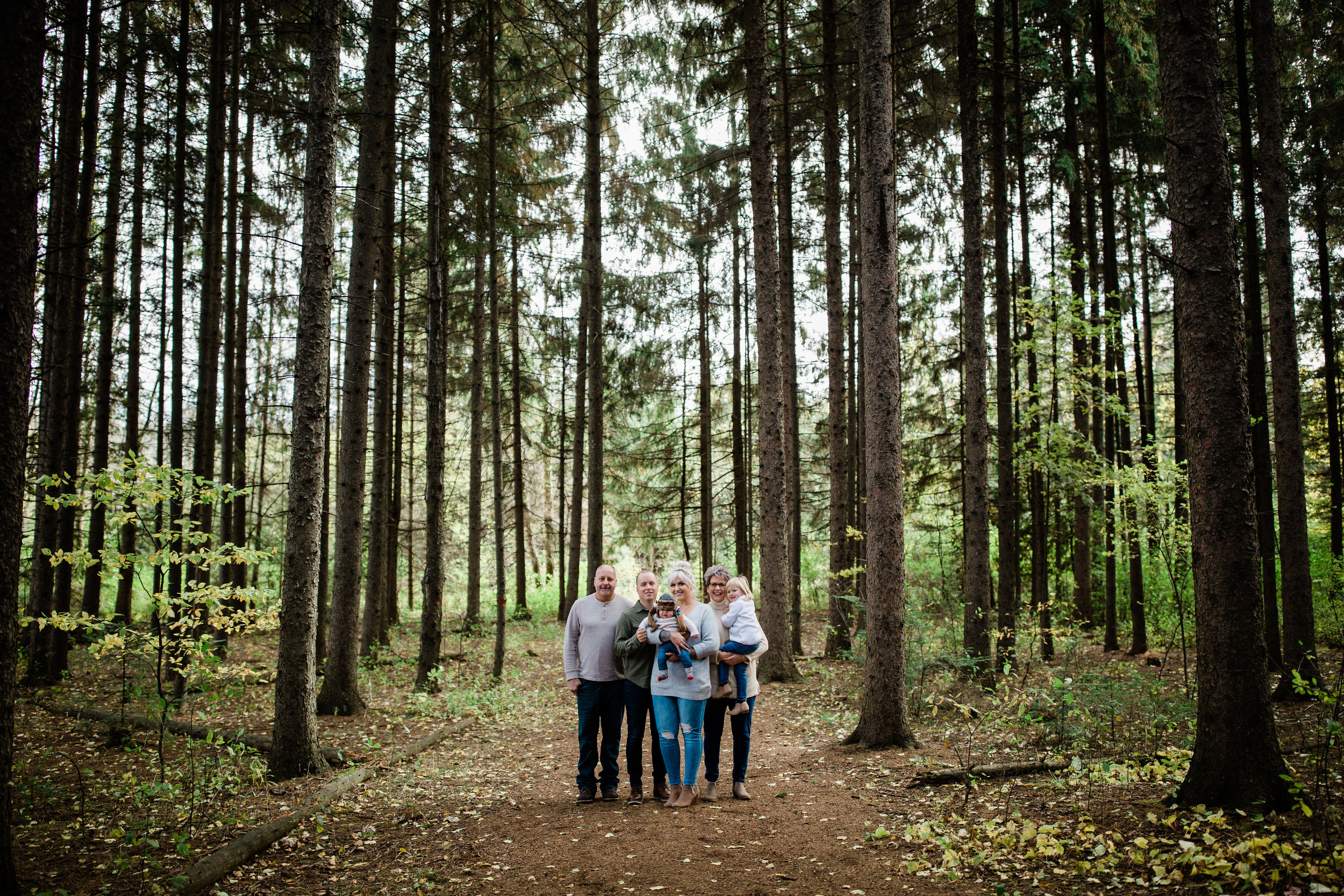 Environmental family portrait with tall slender trees.