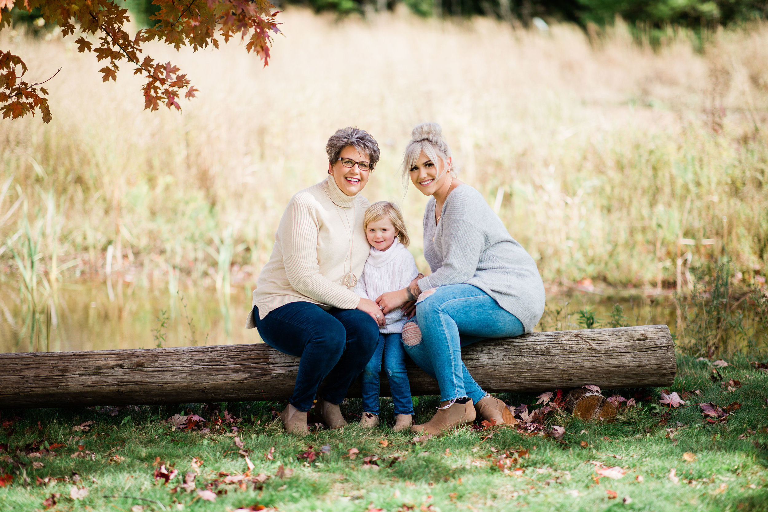 Dianne, Ali, and Myra formal portrait sitting on a log bench. Three generations of women.