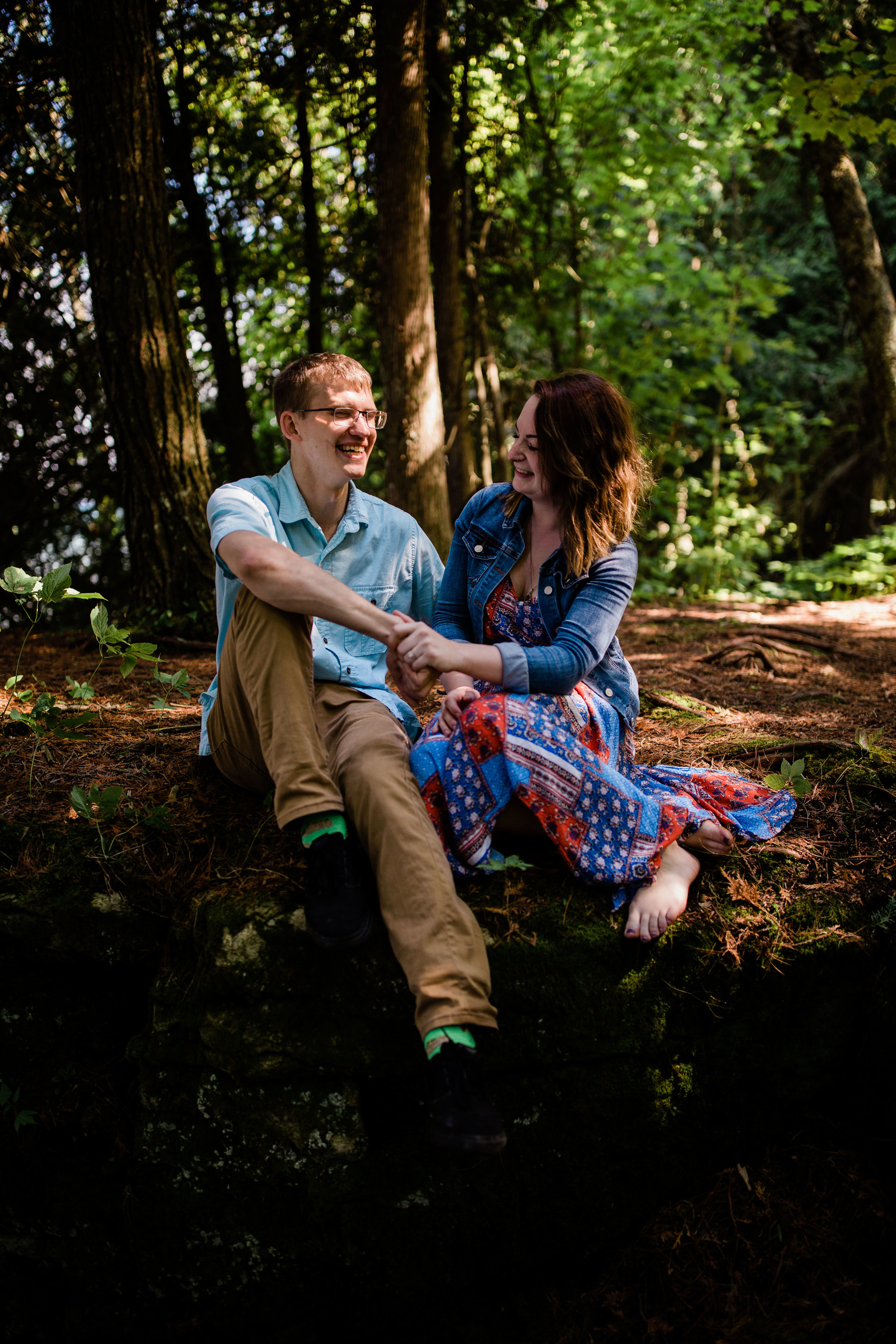 Ben and Lauren sitting in the woods laughing.