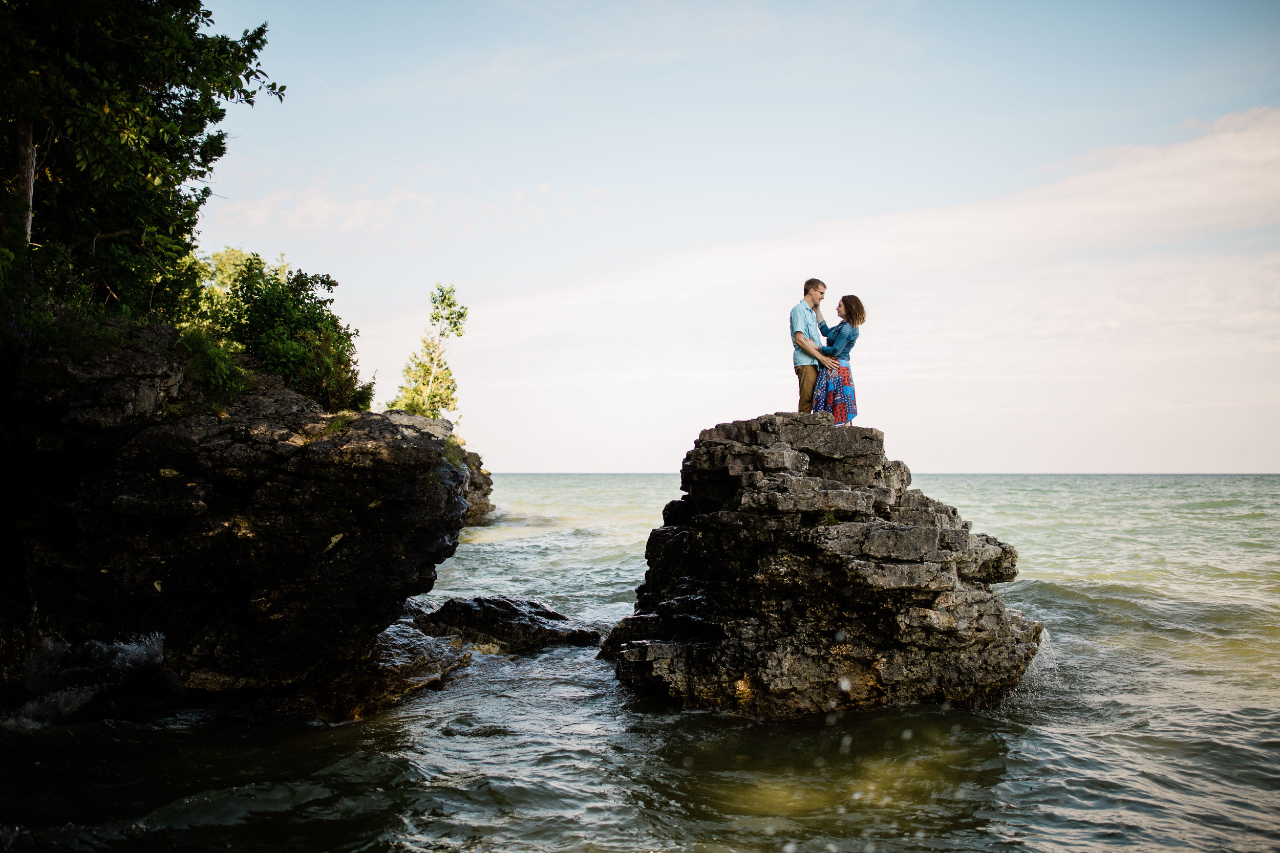 Ben and Lauren embracing each other on a rock island. At Cave Point County Park.