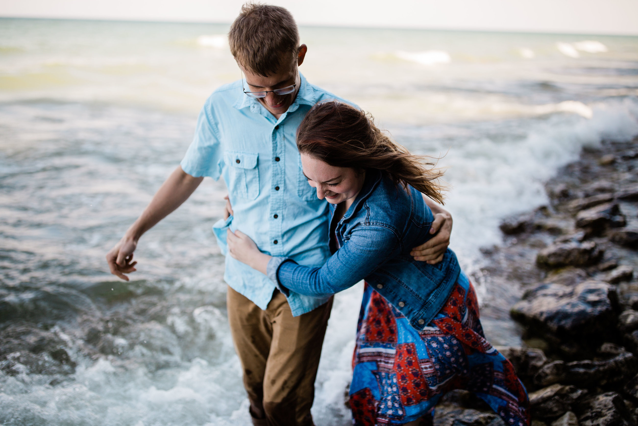 Ben and Lauren walking along the rock beach in the water.