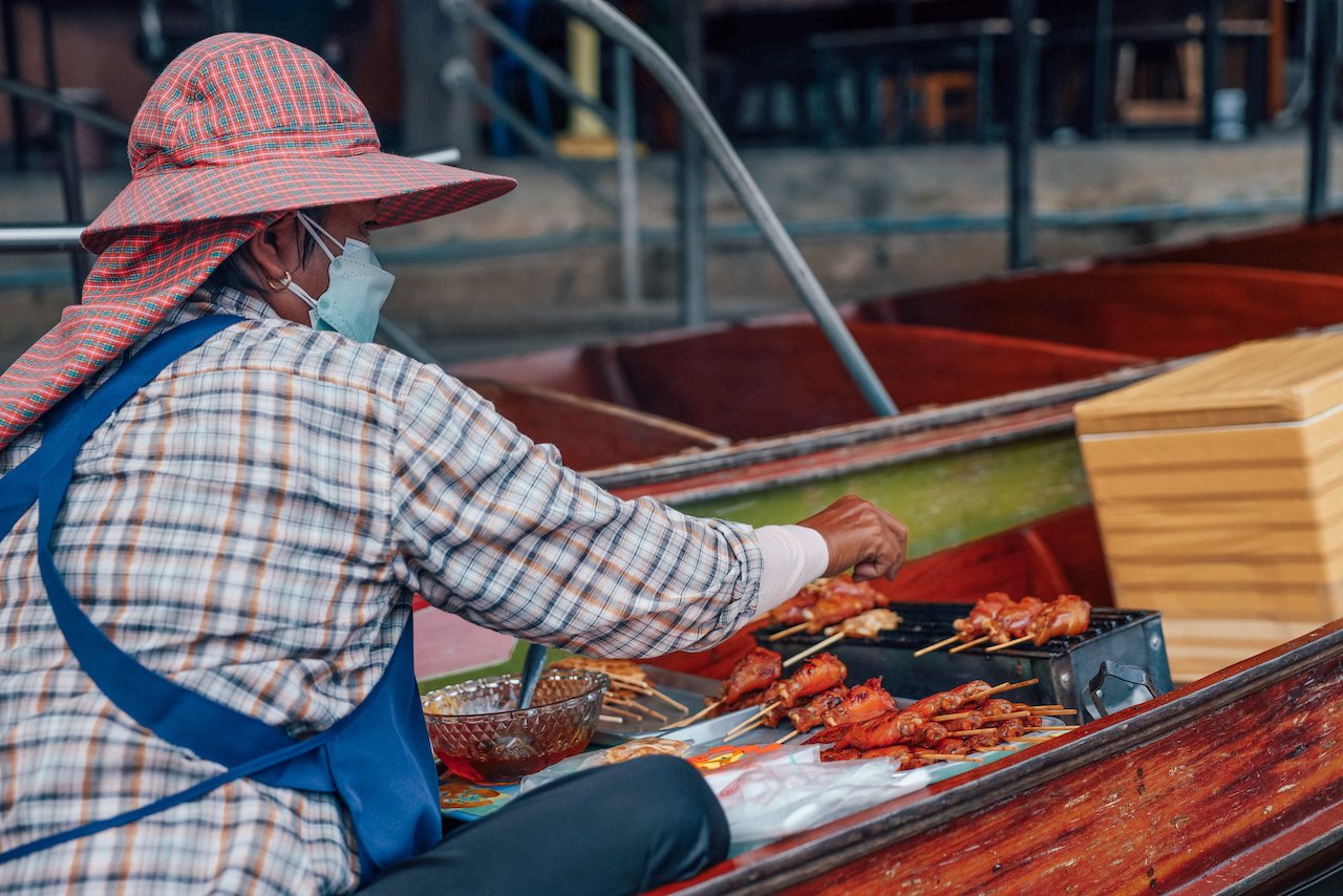 An old lady cooking kebabs - Damnoen Saduak Floating Market - Bangkok - Thailand