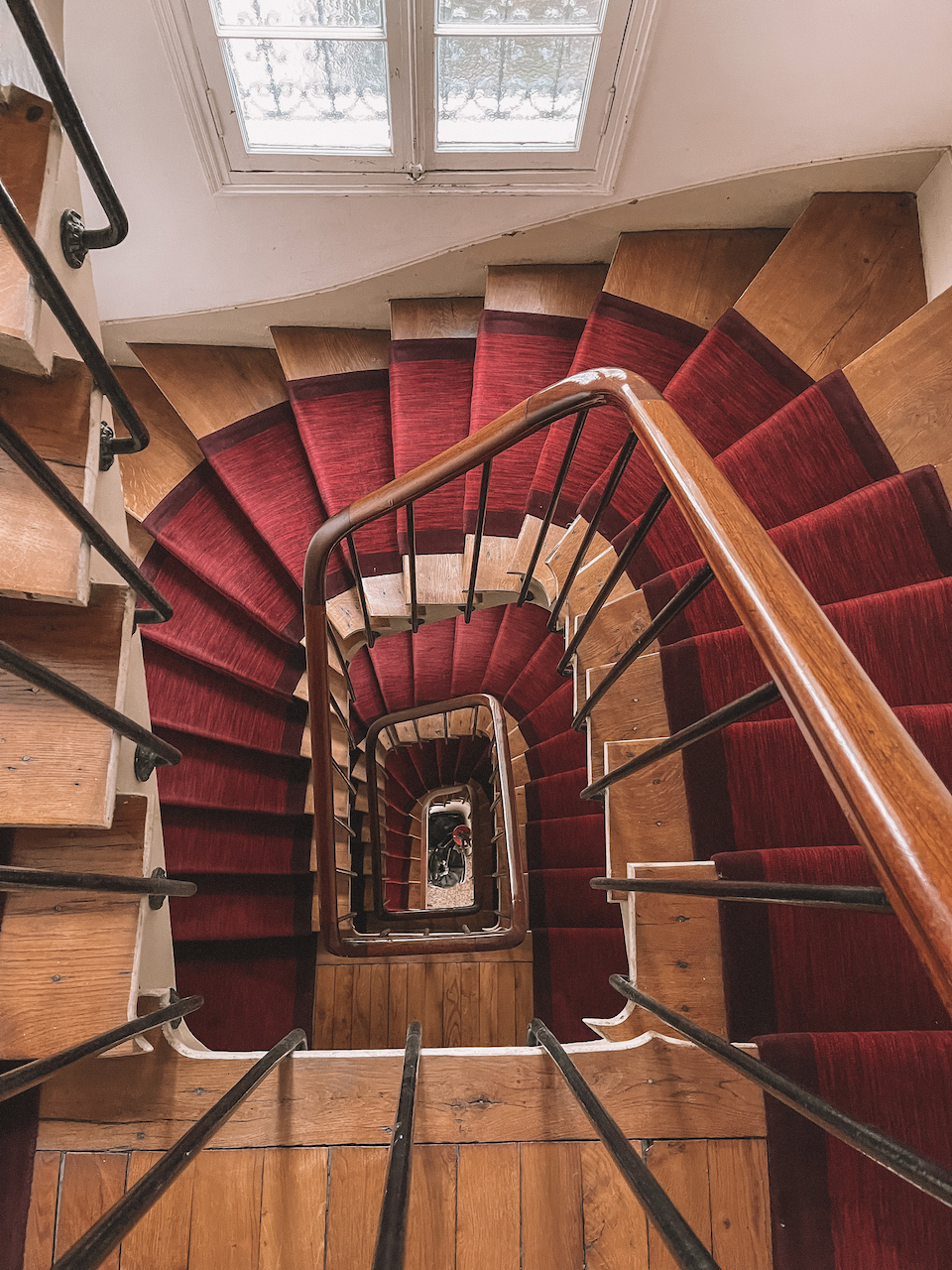 Escalier typique en colimaçon avec tapis rouge dans un immeuble parisien - Paris - France