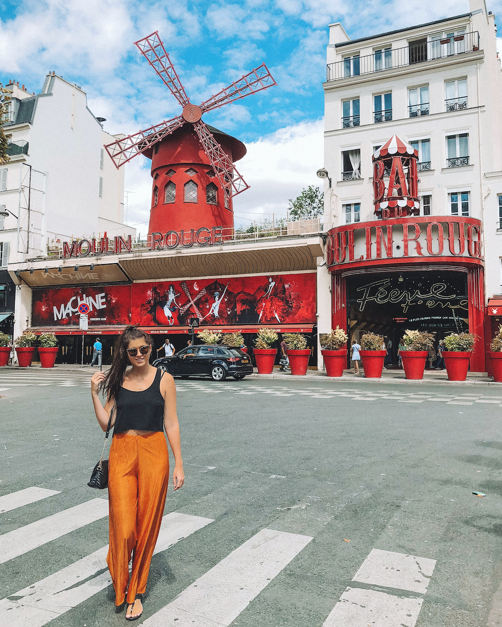 Woman posing in front of the Moulin Rouge during daytime - Paris - France