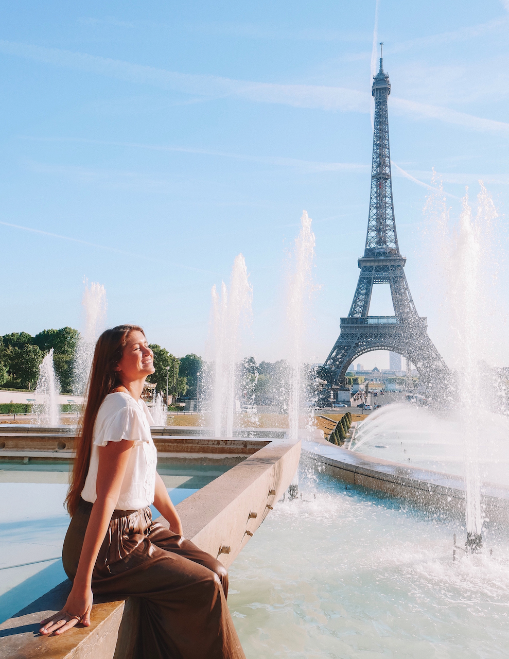 Woman posing at the fountain in front of the Eiffel Tower on a summer day - Paris - France