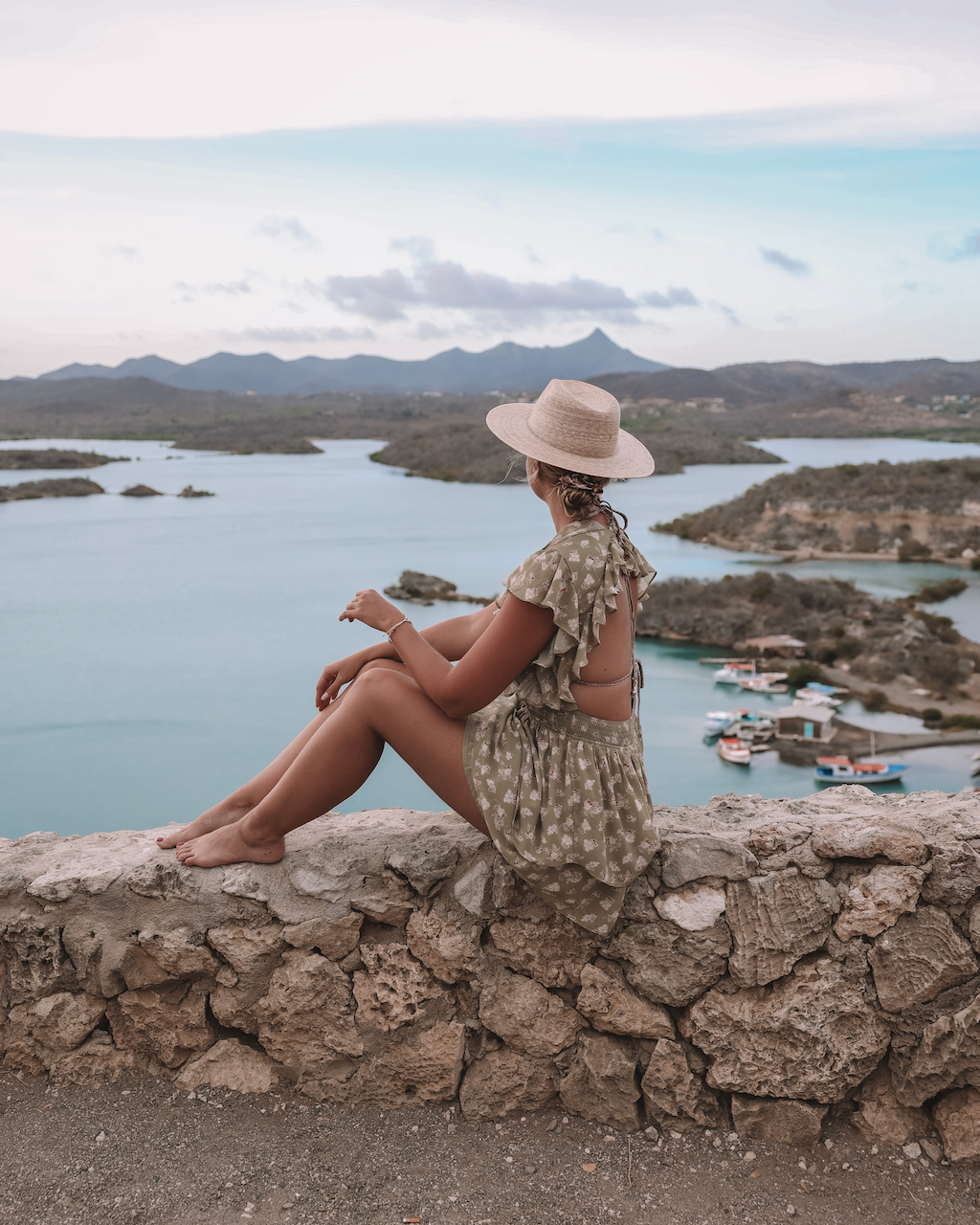 Blond woman in dress and hat looking at the beautiful vista from Santa Martha Lookout - Curaçao - ABC Islands
