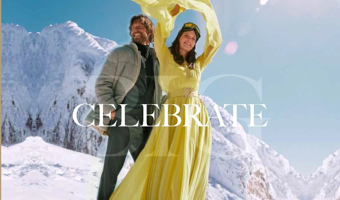A man and woman celebrate together outdoors in the snow, with the woman dressed in a yellow gown and the man in a jacket. The word 'CELEBRATE' is overlaid across the image.