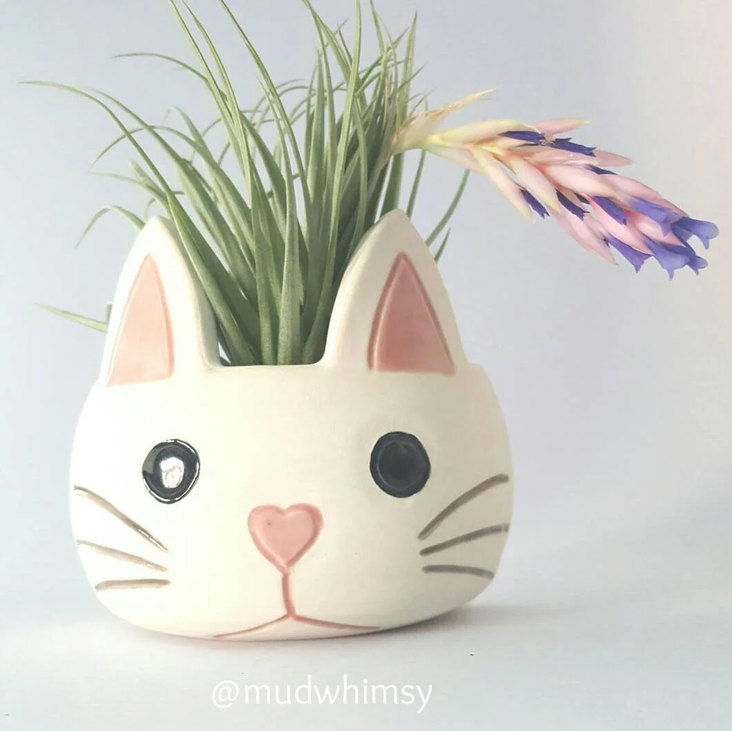  Cute kitty wall pocket made out of porcelain clay. Each one is hand thrown then altered, the ears are attached and the face and features are carved in. The interior and the features are hand painted glazes and the rest is the matte white porcelain.&