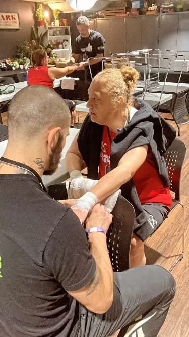 A woman receiving a tattoo from a tattoo artist in a tattoo studio.