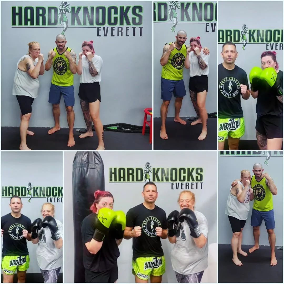 People posing and training at Hard Knocks Everett gym, including fighters with boxing gloves and martial arts gear, in a fitness or martial arts training environment.