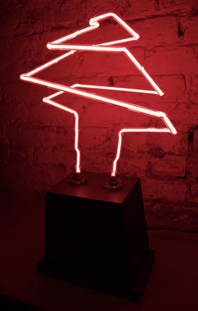 The form and function of the lamp are the antithesis of both a tree and a typical lamp. The wooden form of the base is composed of hard angles and lines not found in trees.