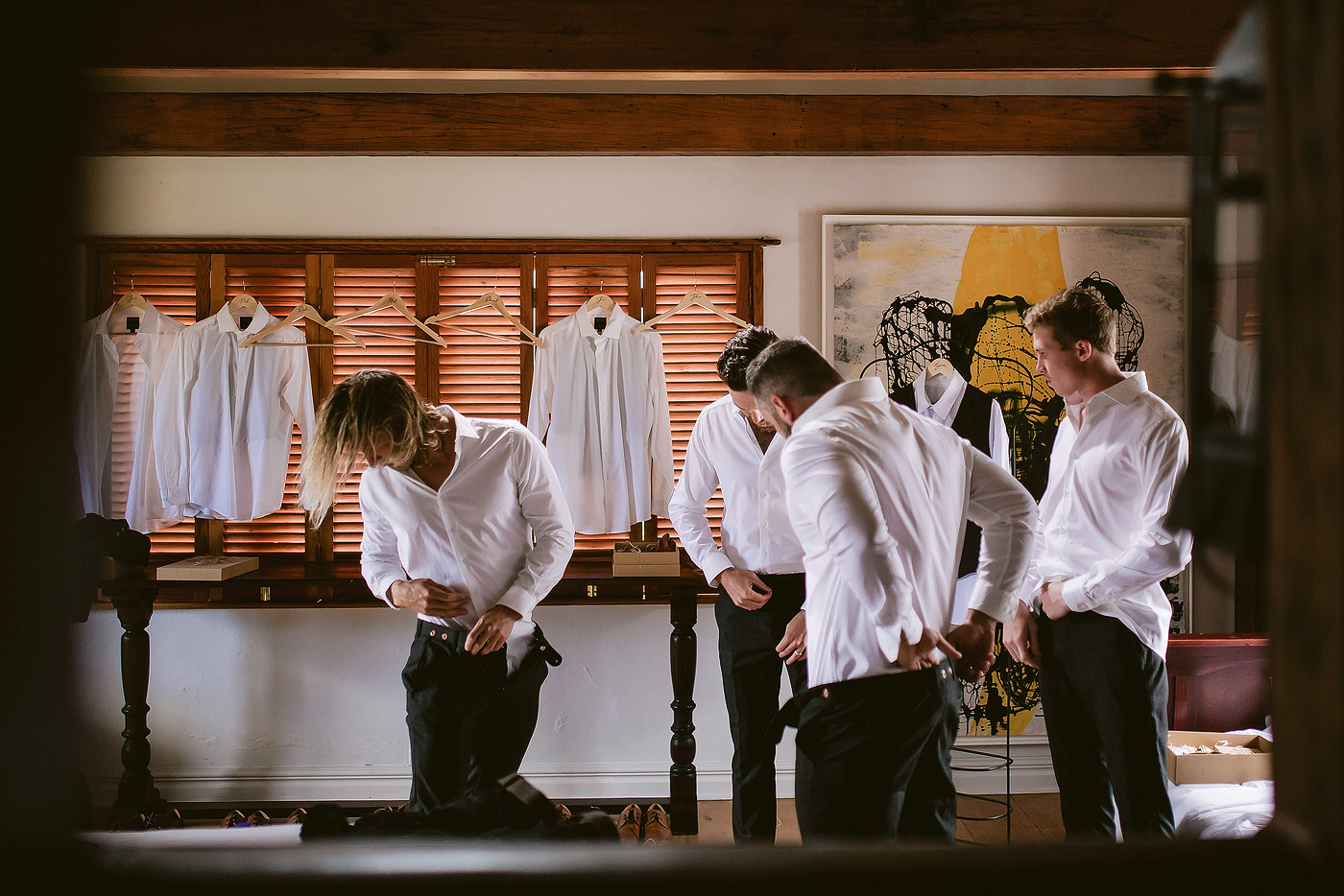 Groom and groomsmen putting on their wedding clothes in the grooms wedding room