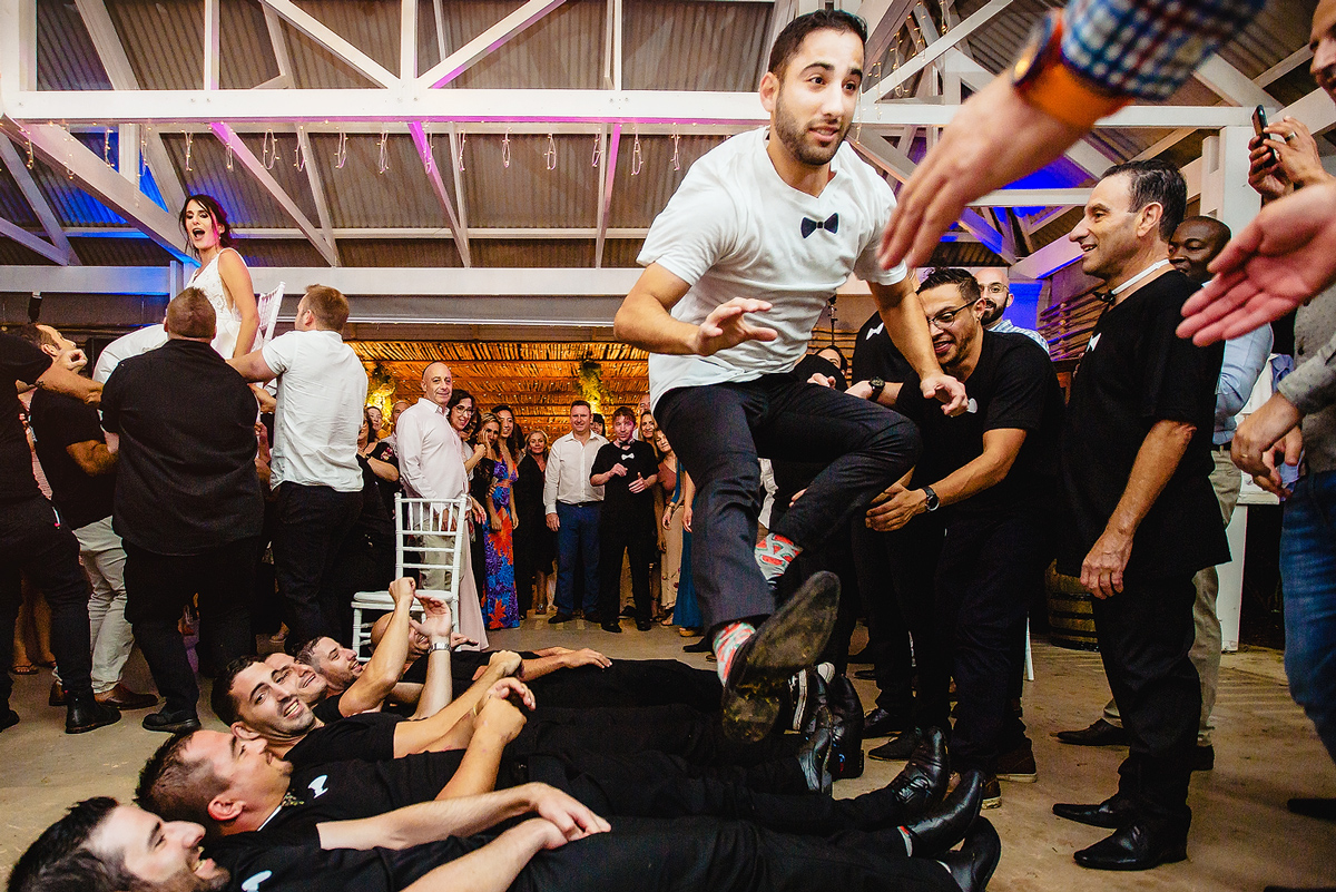 Groom jumping over the groomsmen at the Hora during Jewish Wedding in South Africa