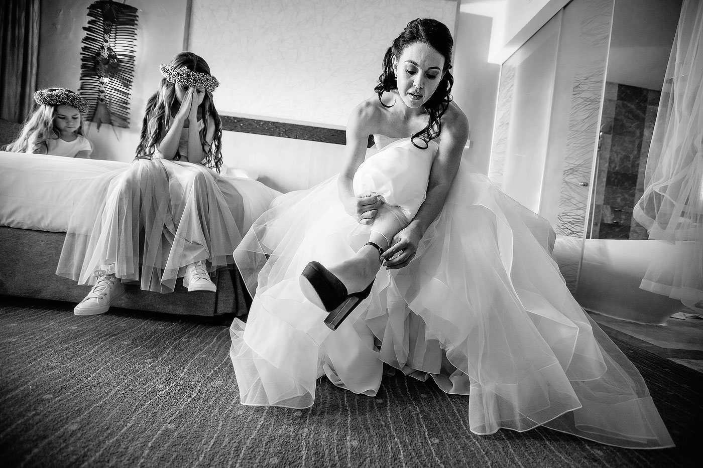 Bride putting on shoes in Bridal Room with Flower Girls