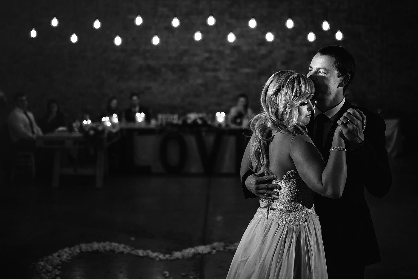 Intimate moment during the wedding first dance with naked bulbs in backround