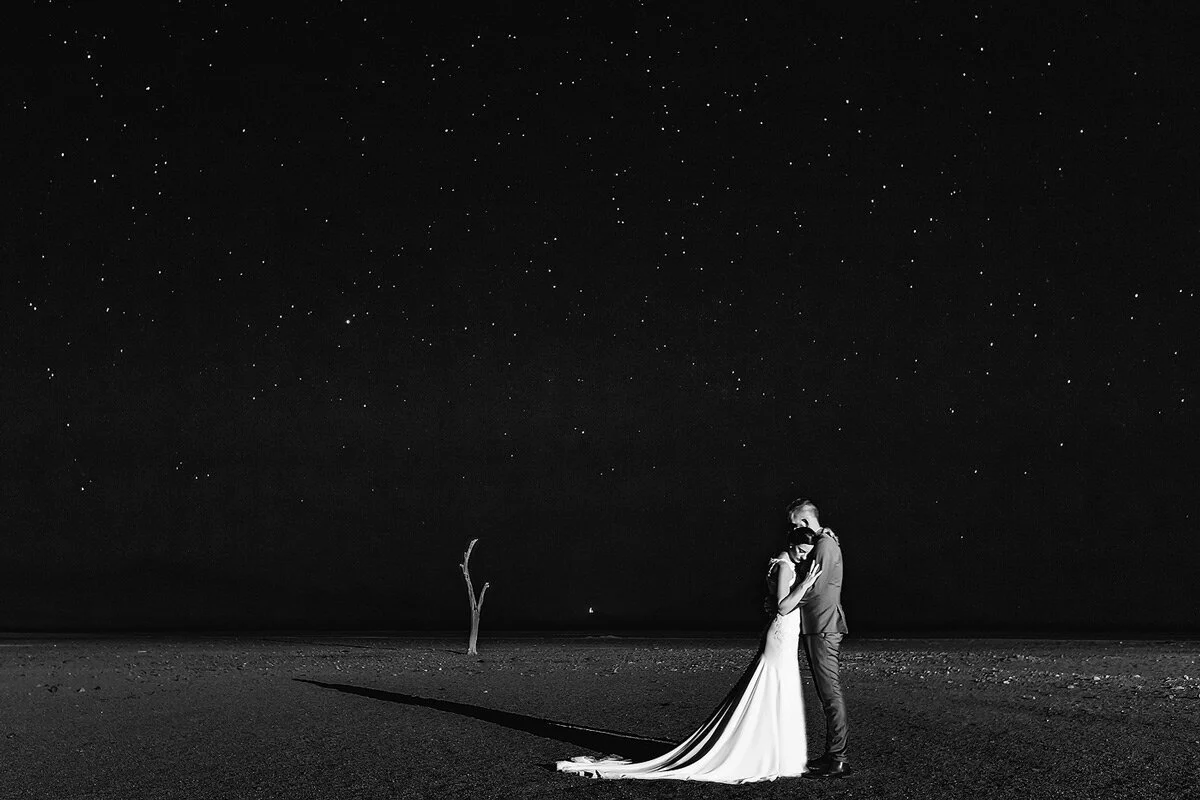 Night Time wedding couple portraits with the bride and groom and the full moon and stars in the Namibian Desert.