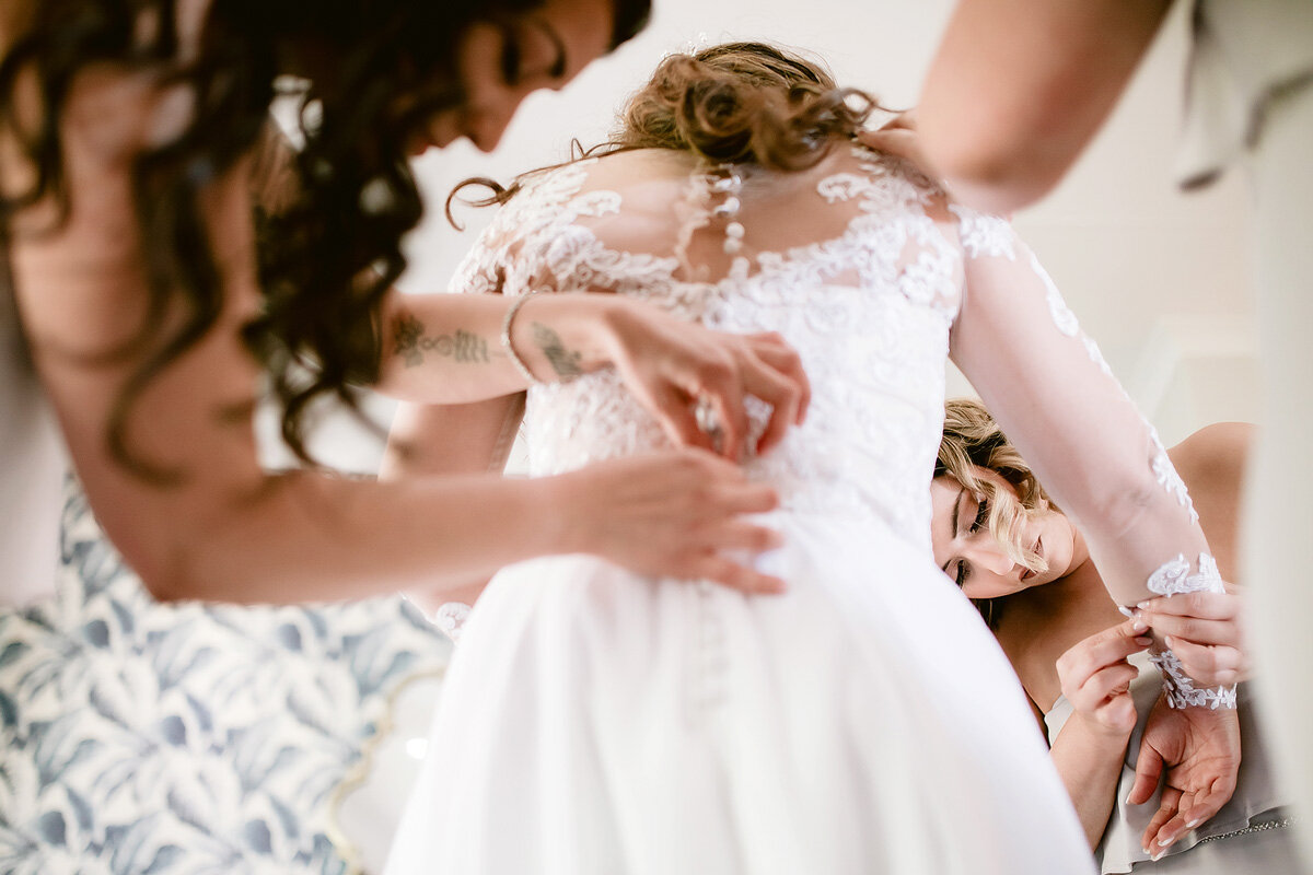 Bridesmaids helping the bride to put on her wedding gown in Northern Cape South Africa.