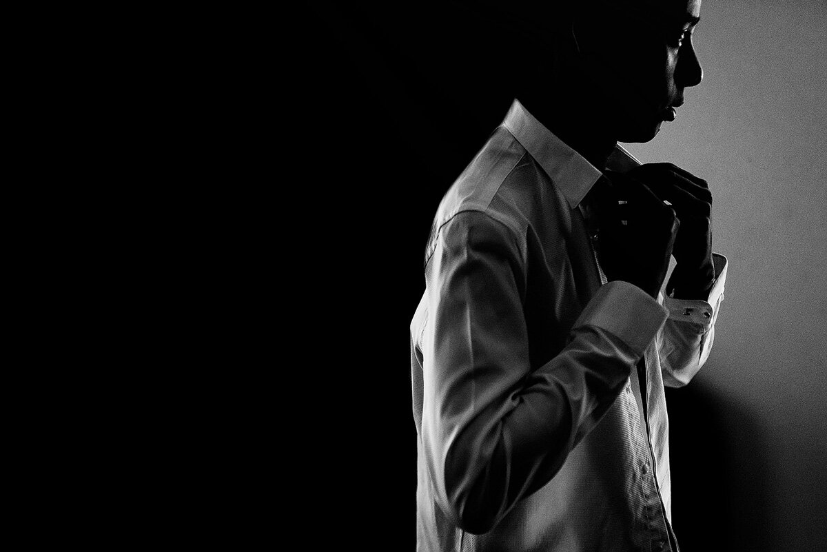 Creative moment of the groom putting on his tie before walking down the aisle.