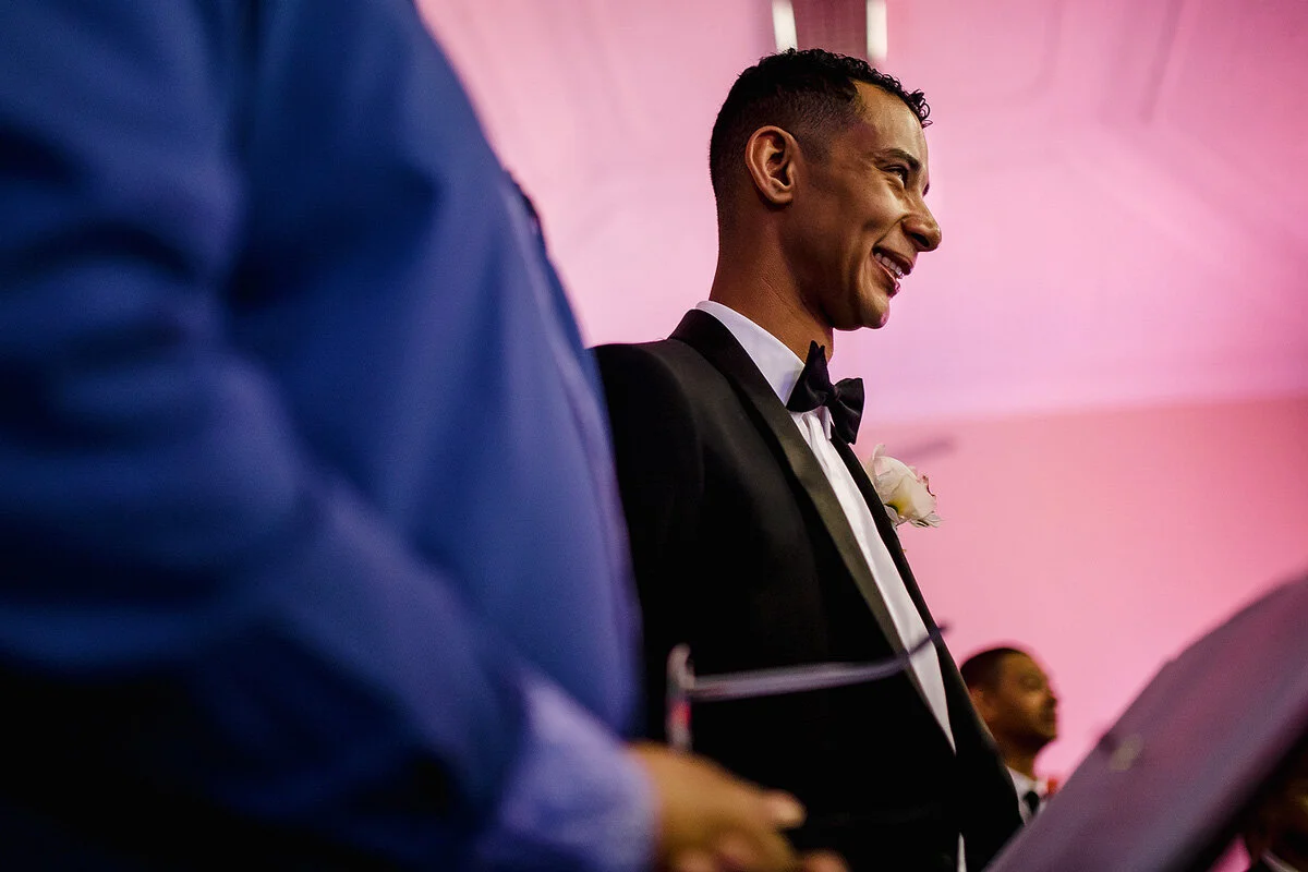 The groom reacts with a smile when he sees his bride for the first time.