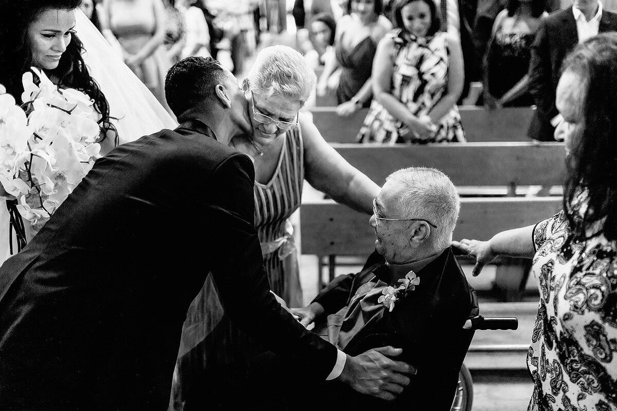 The groom embracing the mother of the bride and father of the bride with the Bride looking on.