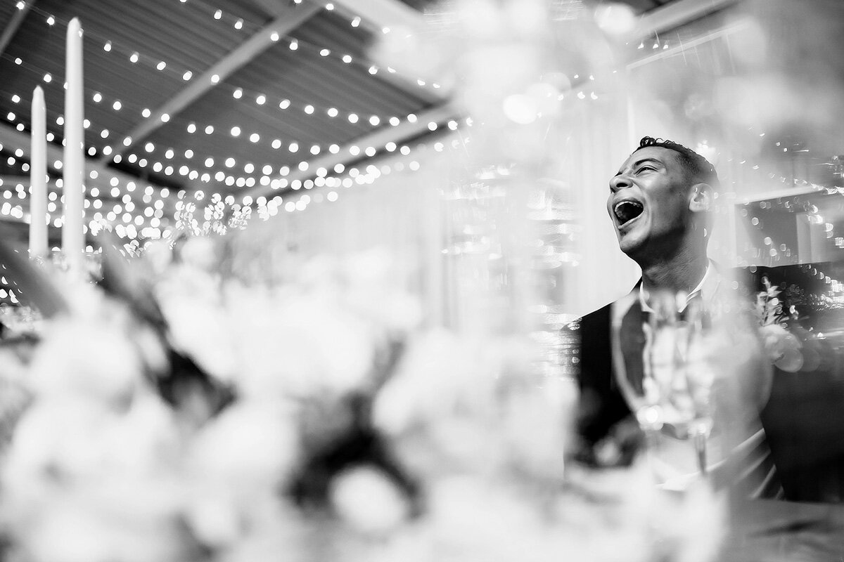 Groom reacts with laughter during the wedding toasts.