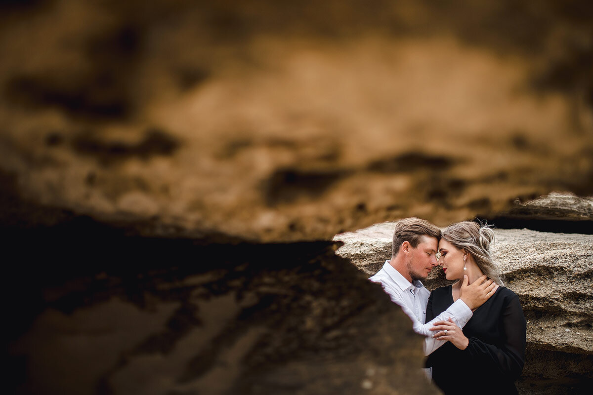 Creative Engagement Portraits underneath rocks with black dress in the Garden Route.
