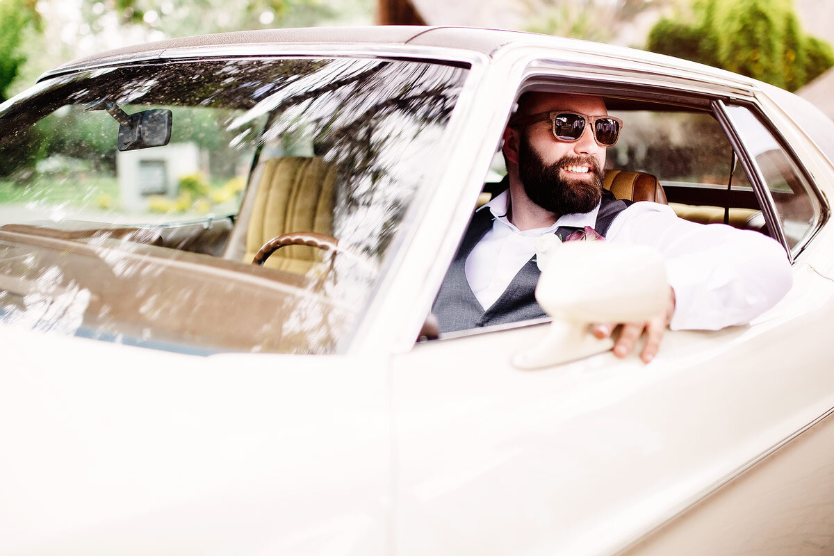 Groom Wedding Portraits with sunglasses in a vintage wedding car in Namibia.