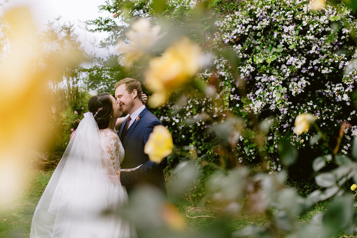 Bride and groom intimate wedding portraits between yellow roses.