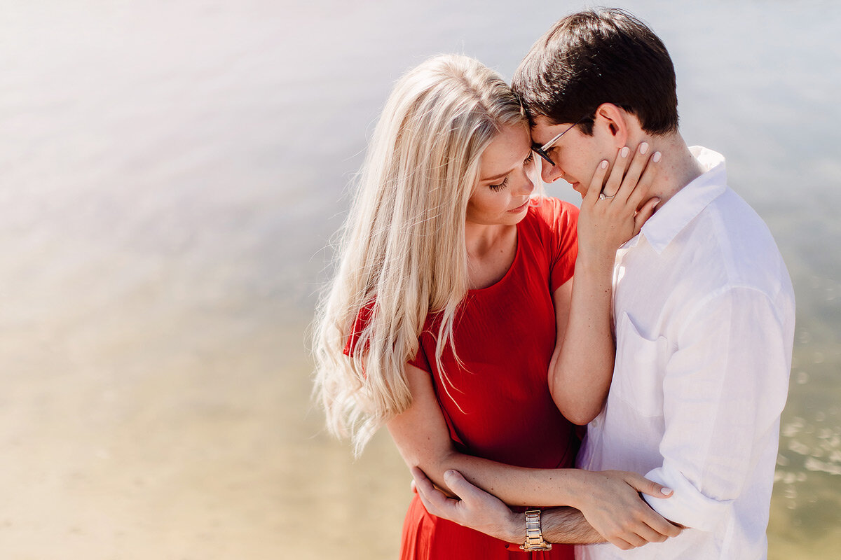 Intimate engagement couple portraits with red dress in water.
