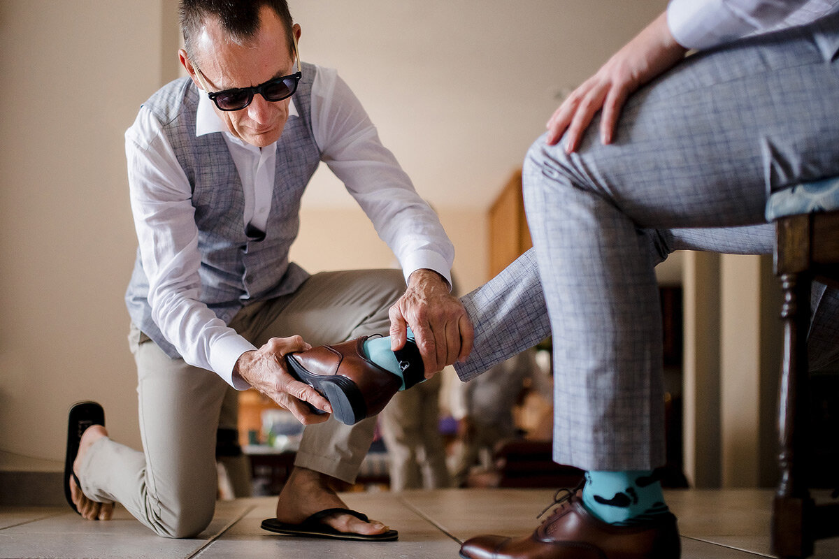 Father of the groom helping his son with his new wedding shoes.