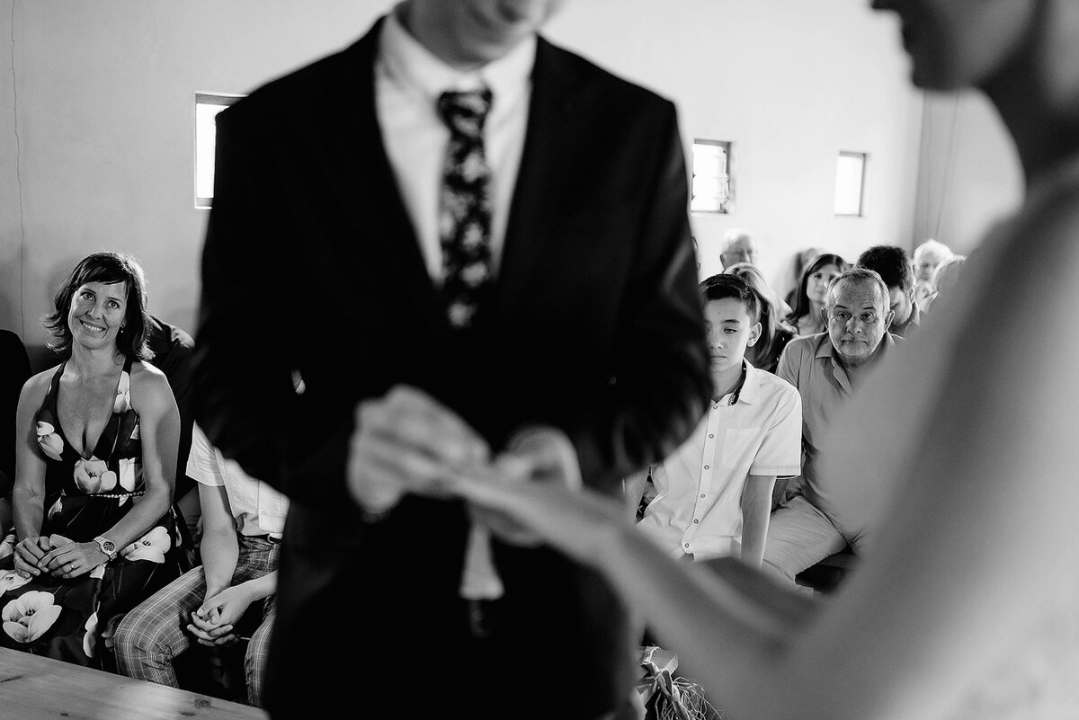 Mother of the groom looking at her son putting the wedding ring on his brides finger.