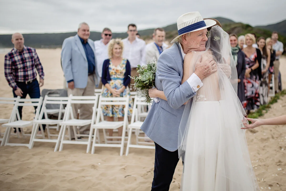 Father and daughter walking down the aisle on the beach.