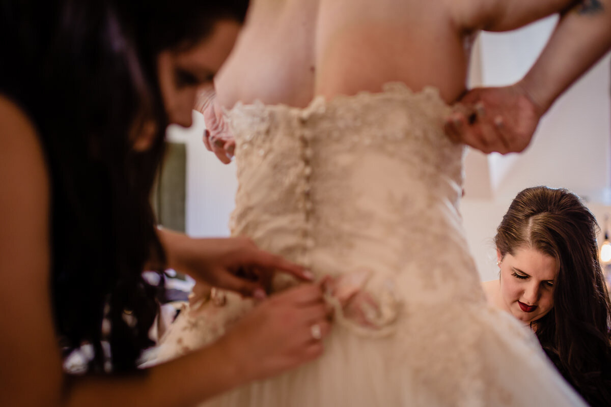 Bride putting on her wedding dress with her bridesmaids in South Africa.